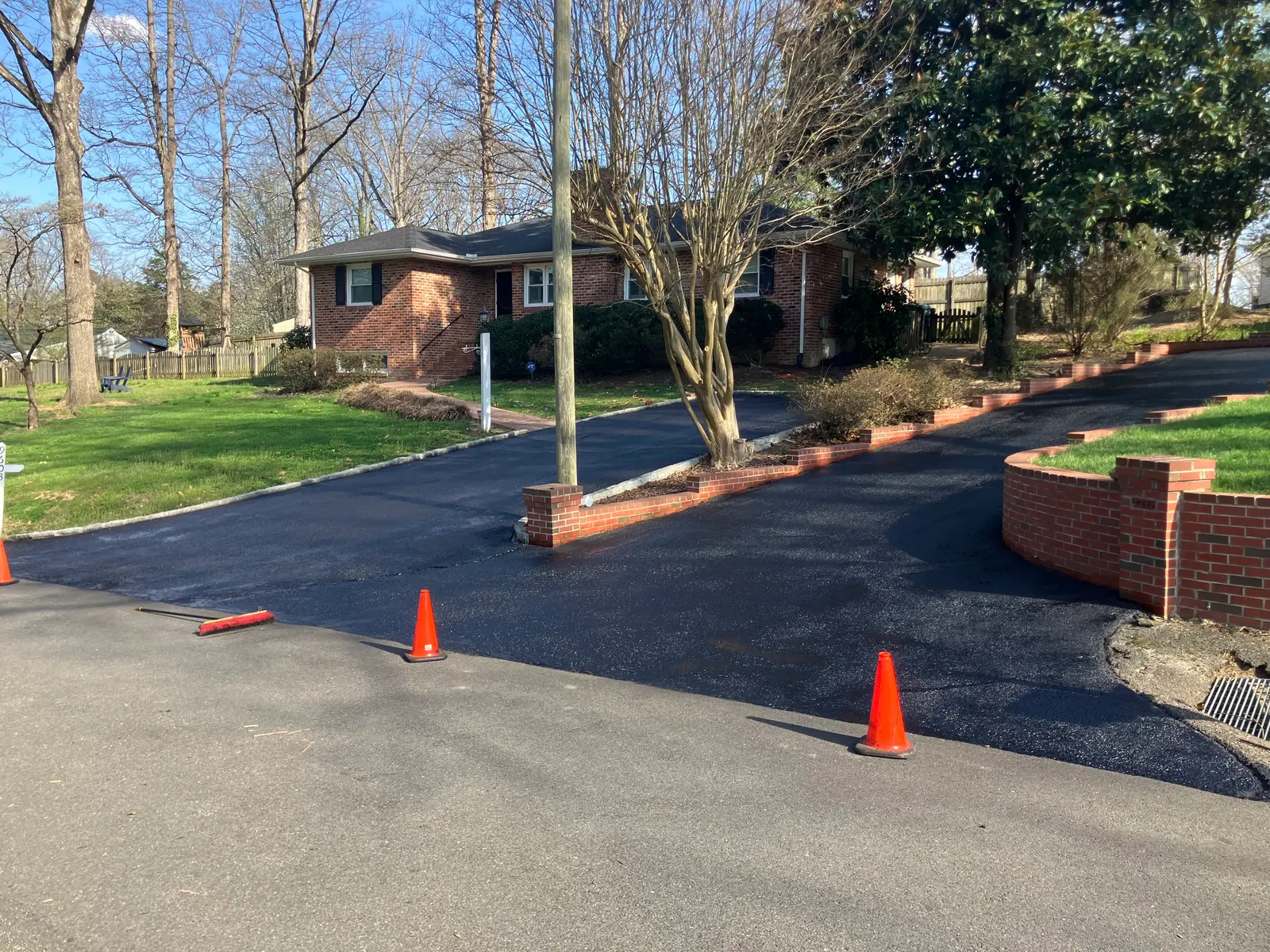Fresh asphalt drive along brick planter walls at a ranch home