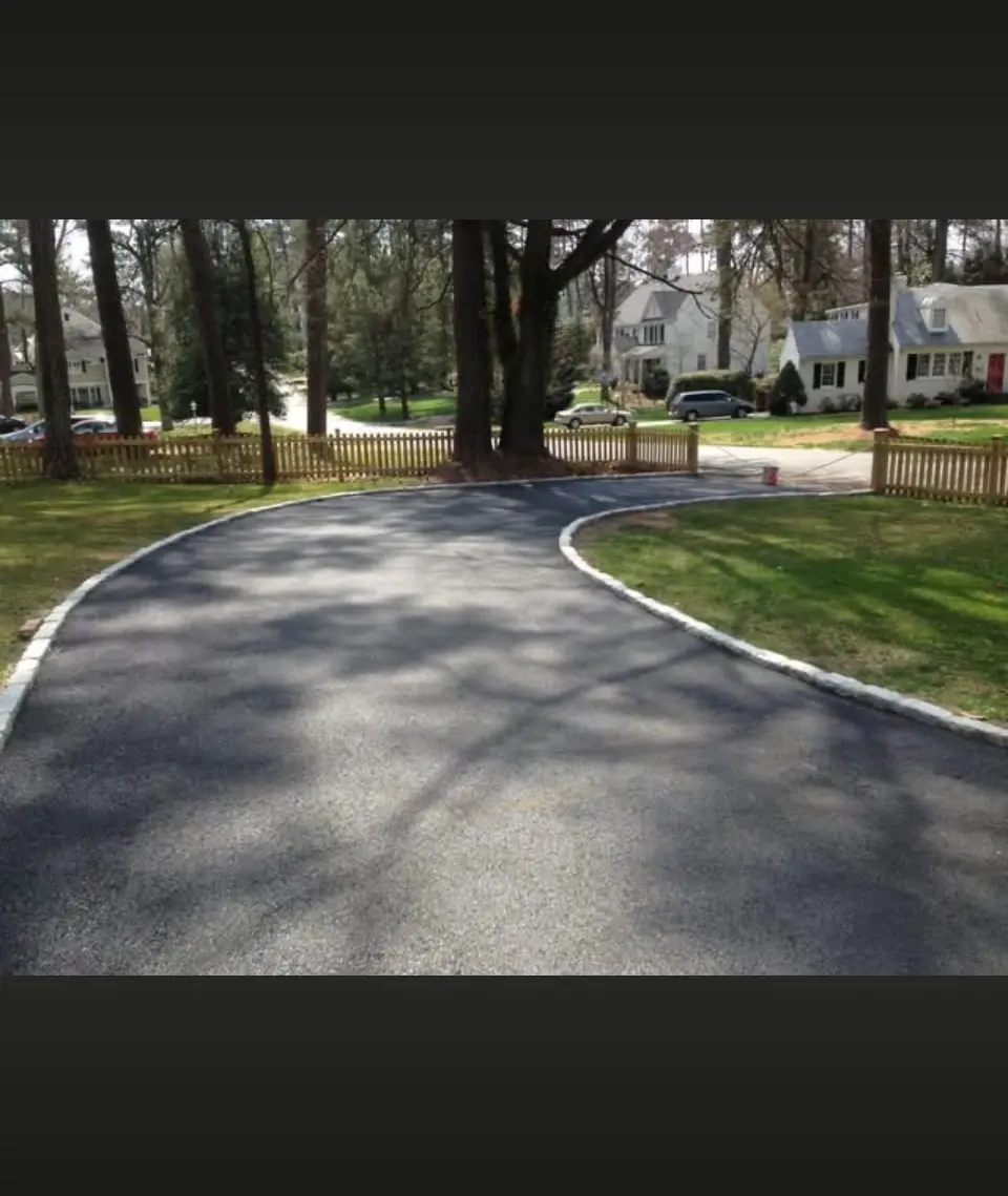 Curved driveway with cobblestone edging along a picket fence