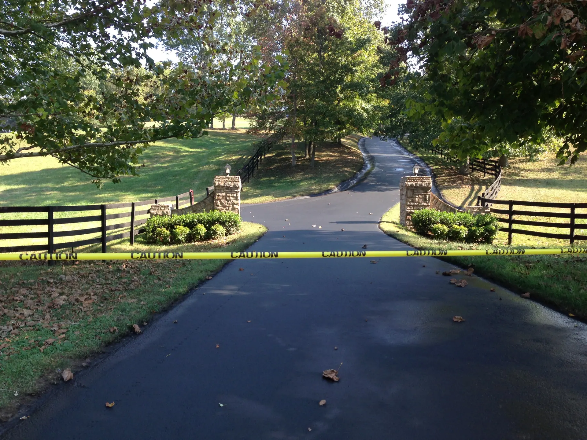 Fresh asphalt drive through a gated stone-pillar entrance