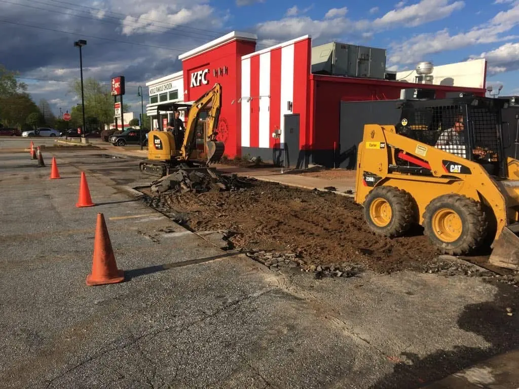 Excavator and skid steer cutting out a KFC drive-thru