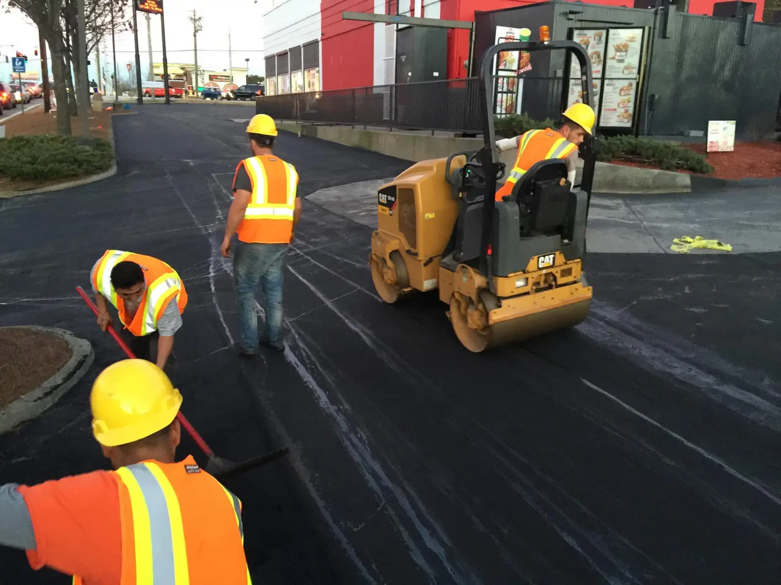 Four-man crew and roller working a KFC drive-thru at dusk