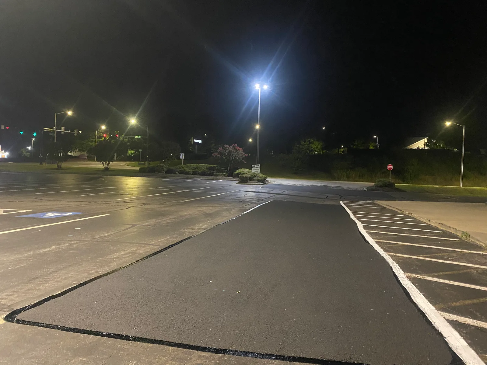 Fresh asphalt patch laid overnight in a sealed and striped commercial lot