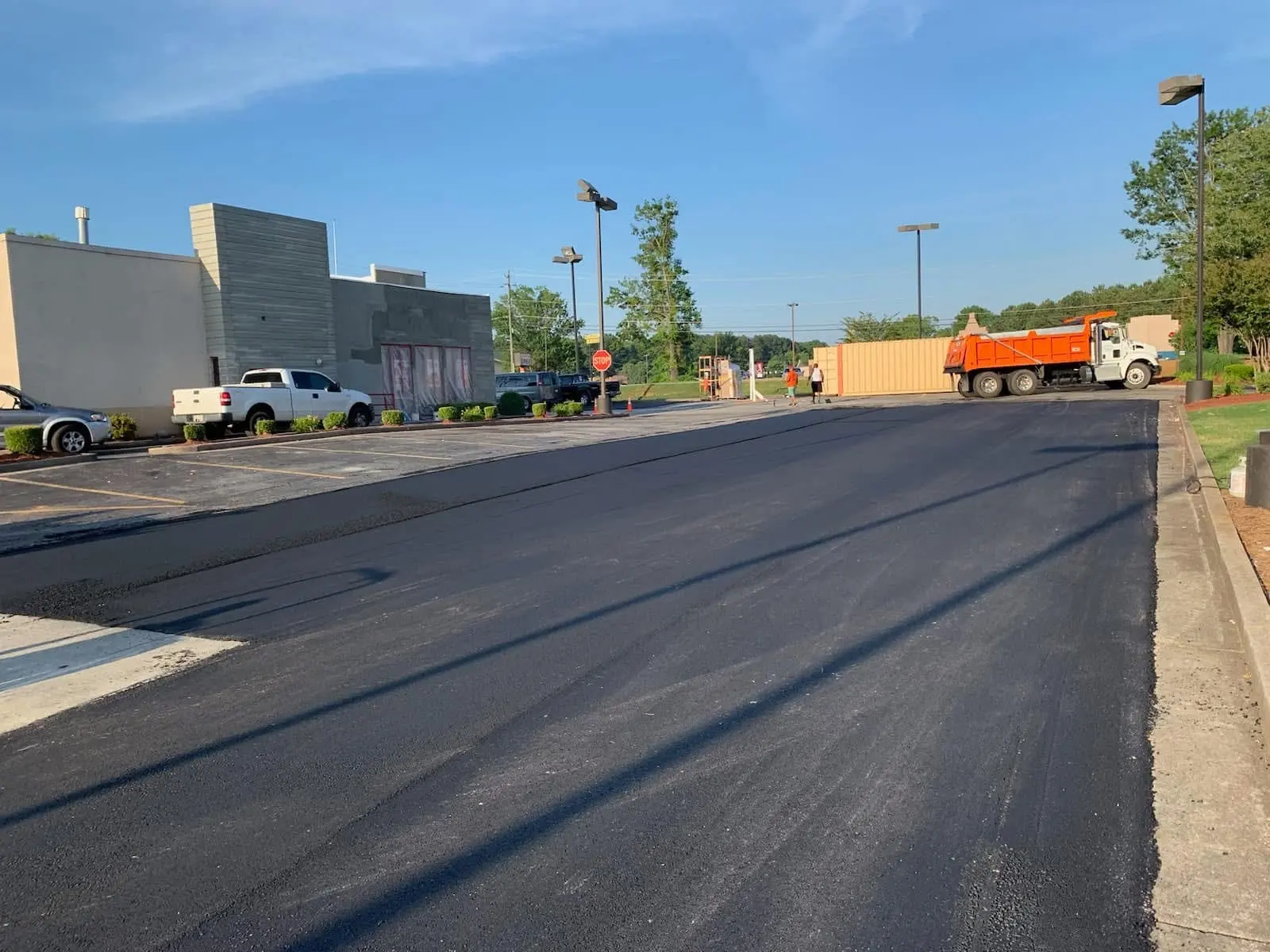 Fresh mat across a commercial lot, dump truck staged