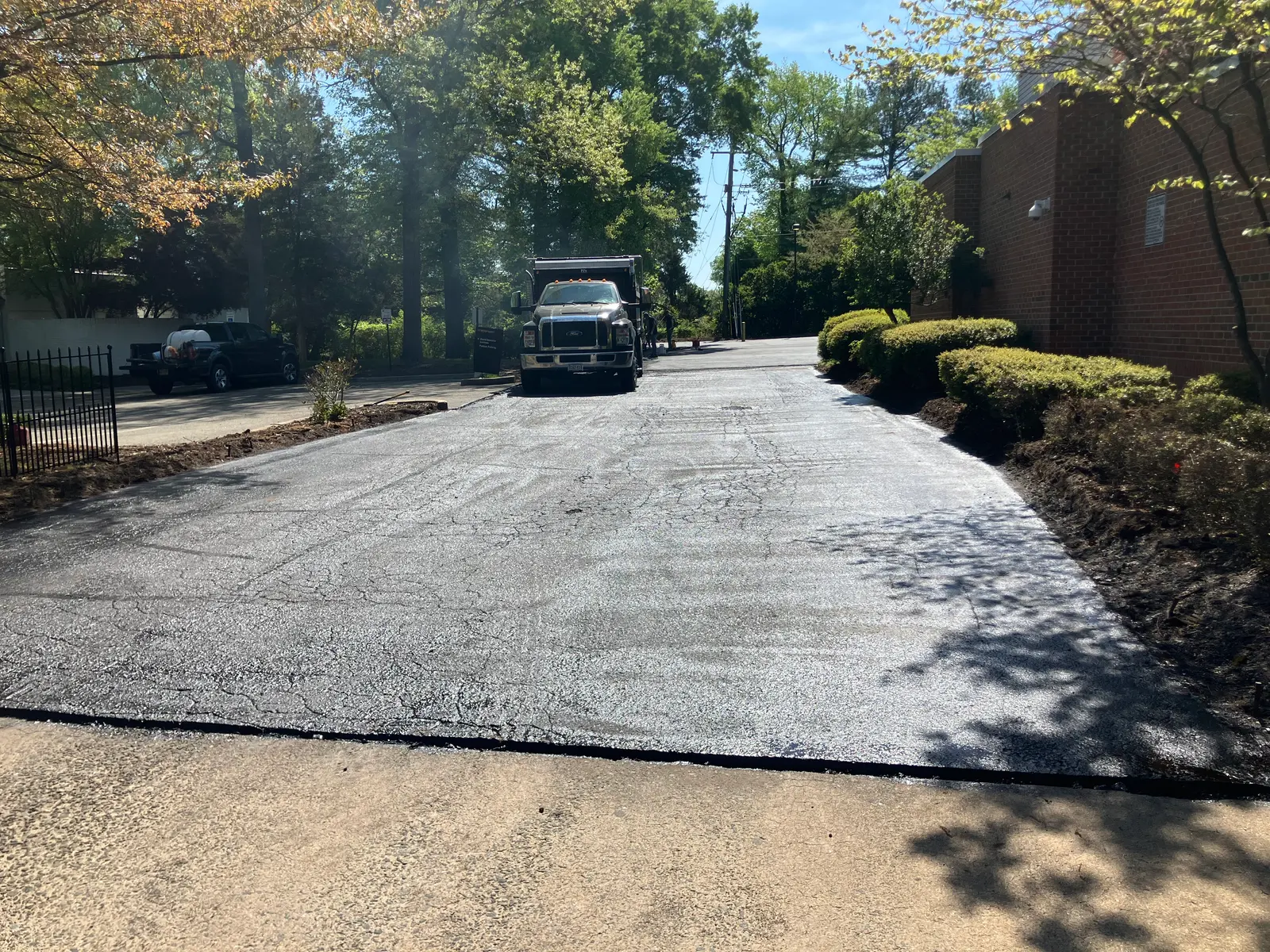 Freshly sealed lane with the dump truck and spray rig on site