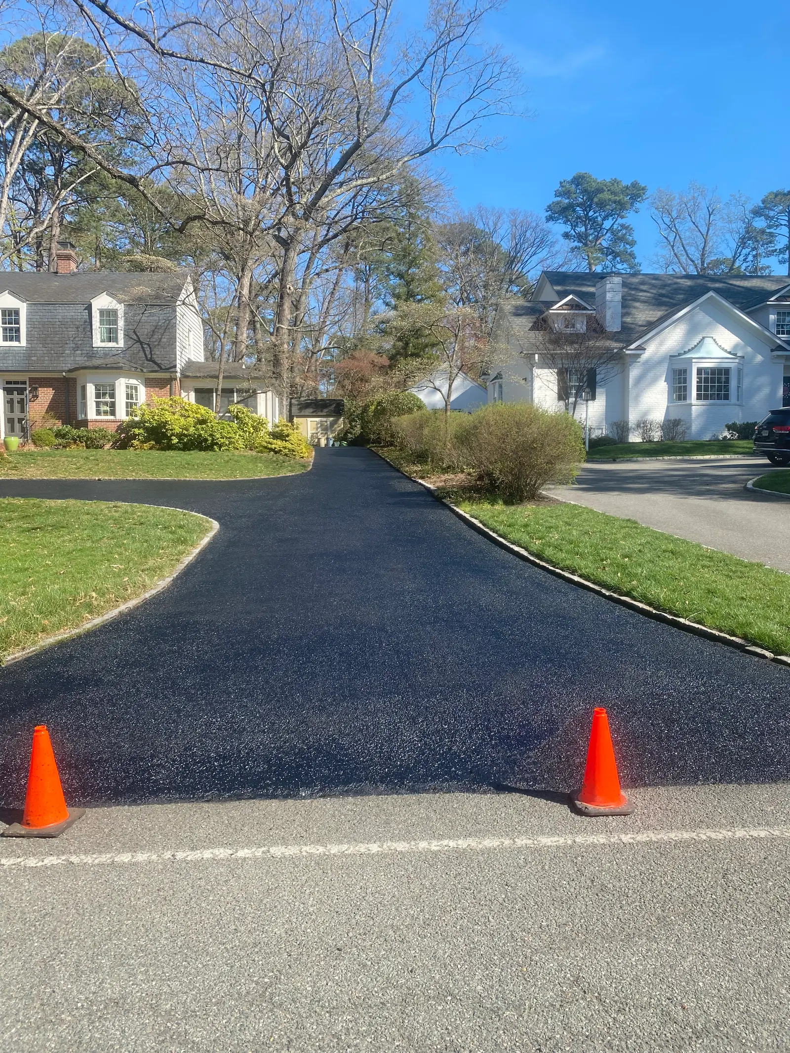 Freshly sealcoated curved driveway between manicured lawns